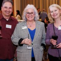 Susan Proctor smiles with two alumni